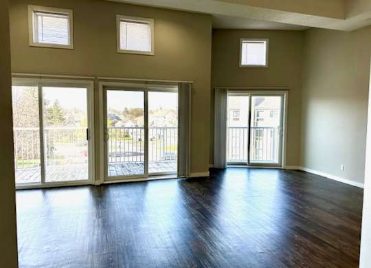 an empty living room with a wood floor and sliding glass doors