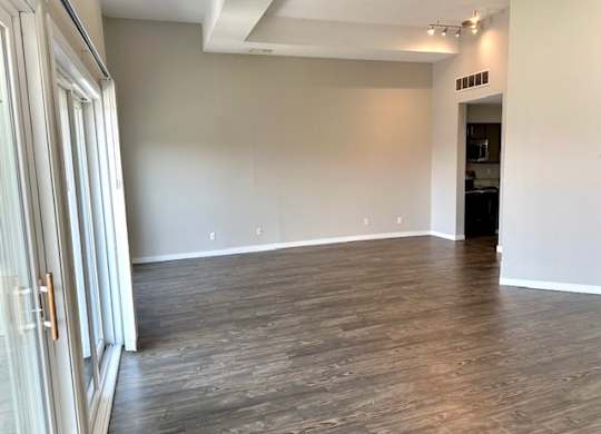 an empty living room with wood flooring and white walls