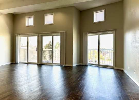 an empty living room with a wood floor and doors