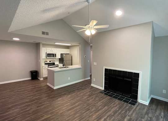 a living room with a fireplace and a kitchen in the background