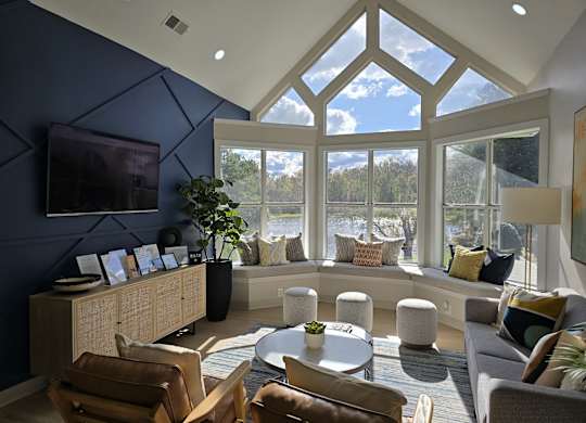 A living room with a large window and a TV on the wall.