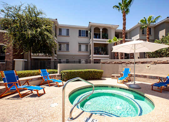 Phoenix, AZ Apartments - Ironhorse at Tramonto - Outdoor Sparkling Spa With Lounge Seating and View of Apartment Building