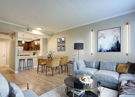 Apartments in Walnut Creek, CA, for Rent - Ivy Hill - Living Room with Hardwood Floor, Area Rug, Large Sectional Couch, Round Coffee Table, High Ceilings, and Direct Access to Dining Area and Kitchen.