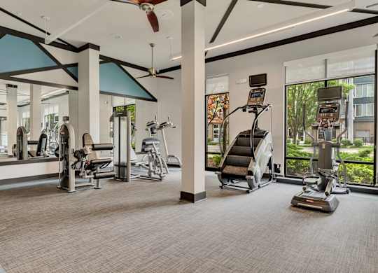 a gym with exercise equipment and windows at the estates apartments