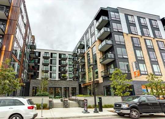 A modern apartment complex with cars parked in front.