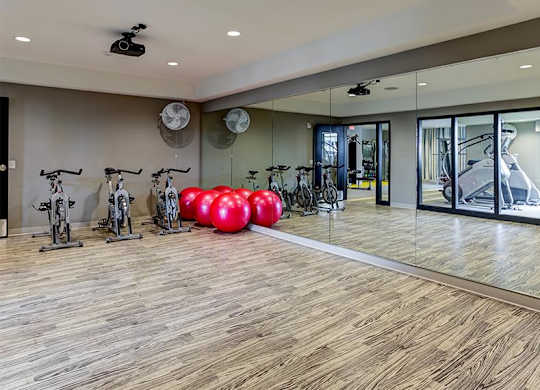 A room with a wooden floor and a glass wall with a reflection of a bicycle.