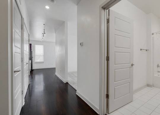 a renovated living room and kitchen with white walls and wood floors