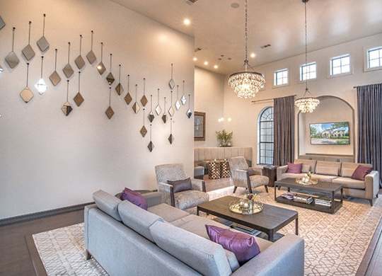 A living room with a grey couch and a chandelier.