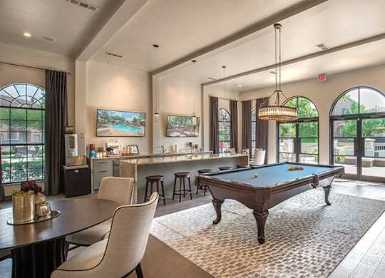 A well-lit room with a pool table and comfortable seating.