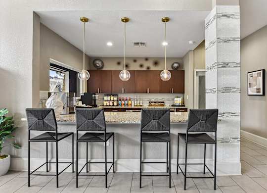 A kitchen with a bar area and four black chairs.
