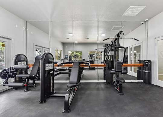 A spacious gym with a variety of equipment including treadmills, weights, and a bench press.