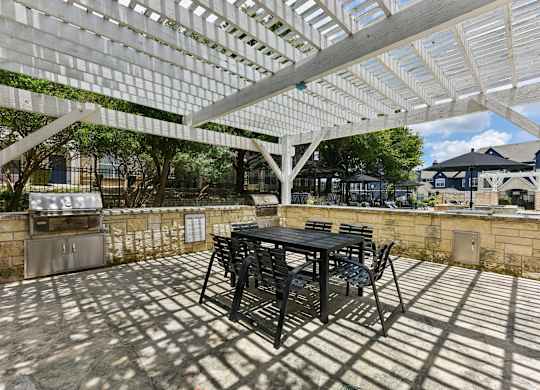 A patio with a table and chairs under a white pergola.