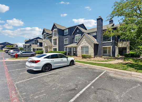 A white car is parked in a parking lot in front of a blue building.