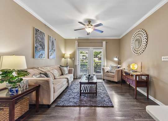 A well-lit living room with a sofa, a coffee table, and a ceiling fan.