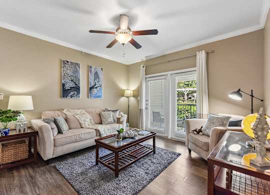 A living room with a couch, a coffee table, and a ceiling fan.