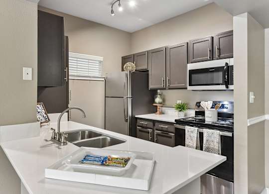 A kitchen with a white counter top and a sink.