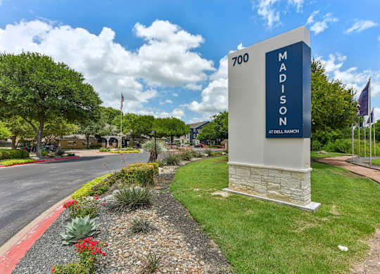A sign for Madison at Dell Ranch stands in front of a landscaped area.