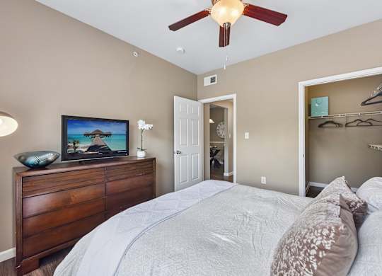 A bedroom with a large bed and a ceiling fan.