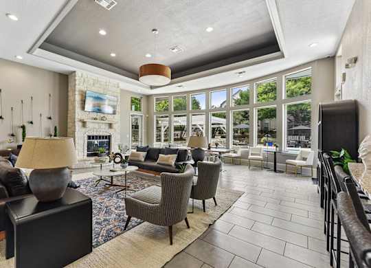 A well-lit living room with a stone fireplace and a variety of seating options.