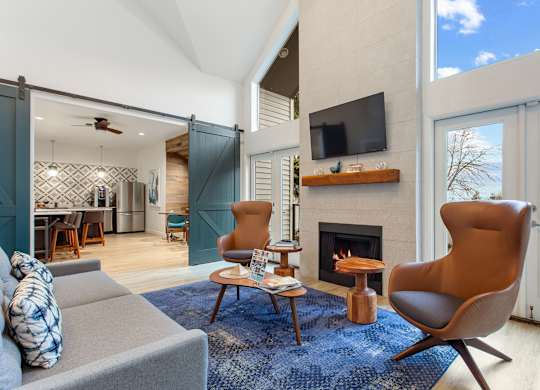 A living room with a grey couch, a brown chair, and a fireplace.