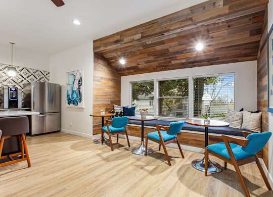 A kitchen with a wooden ceiling and a dining table with chairs.