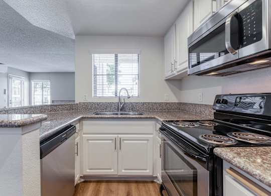 2-Bedroom Apartments in La Jolla, CA - Mirada at La Jolla Colony - Kitchen with Granite Countertops, White Cabinets, Wood-Style Flooring, and Stainless Steel Appliances