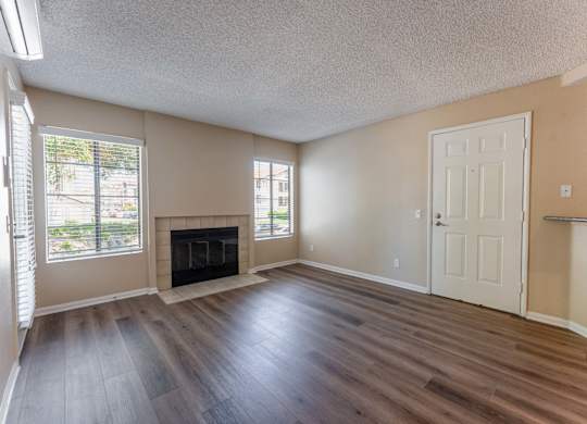 an empty living room with wood flooring and a fireplace
