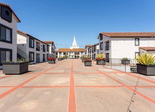 an empty parking lot with buildings and a church in the background