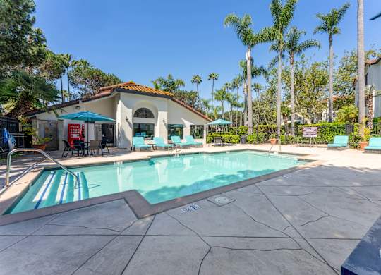 Apartments in La Jolla, CA for Rent - Mirada at La Jolla Colony - Swimming Pool with Lounge Chairs, Umbrellas, Tables with Chairs, and Beautiful Landscaping