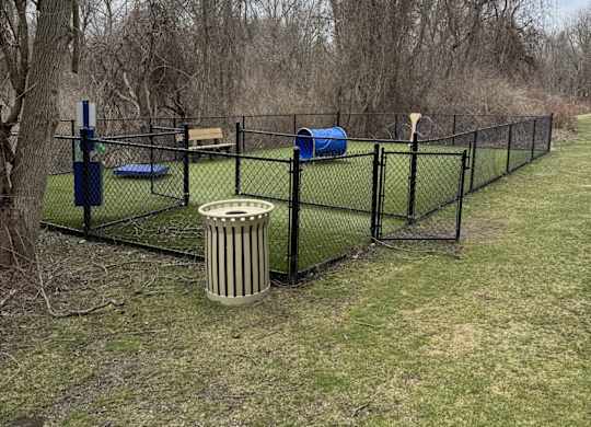 A fenced area with a blue object and a trash can.