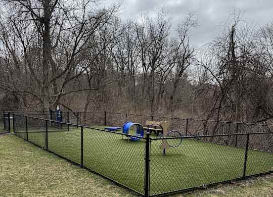 A black fence encloses a green net and a blue object.
