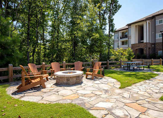 A patio with a fire pit and chairs.
