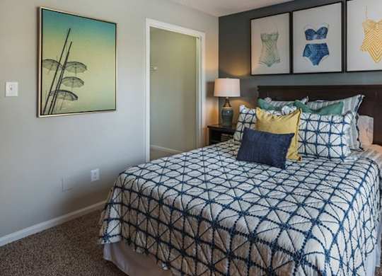 A bedroom with a bed, nightstands, and pictures on the wall.