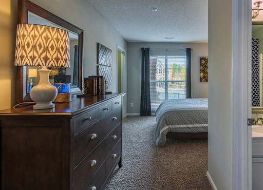 A bedroom with a bed, dresser, and mirror.