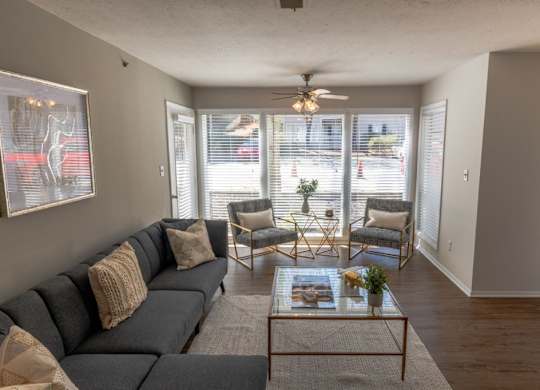 Apartments in Alpharetta, GA for Rent – Webb Bridge Crossing – living room with a couch and two chairs, hardwood floors, ceiling fan and large windows