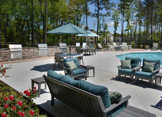 A pool area with a blue umbrella and chairs.