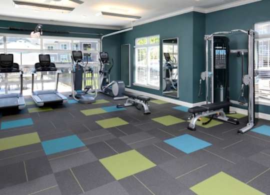 A gym with a variety of equipment including treadmills, weights, and exercise machines.