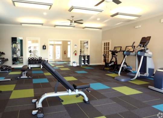 A gym with a variety of equipment including a weight bench, treadmill, and exercise bike.