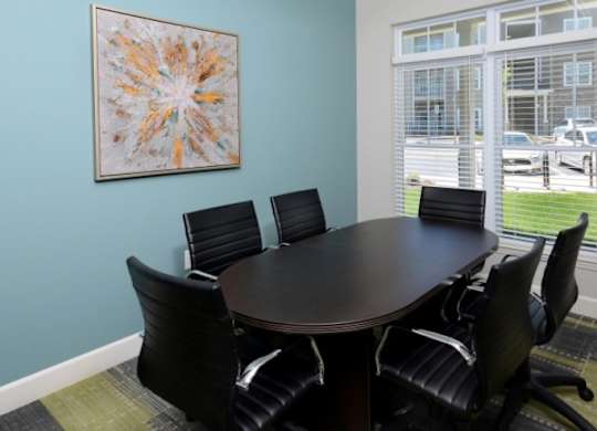 A conference room with a table and chairs and a framed picture on the wall.