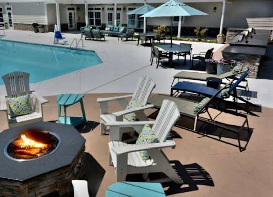 A fire pit sits in the middle of a patio with chairs around it.