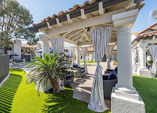 a patio with blue and white striped curtains and lawn furniture