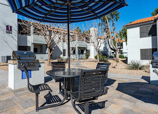 A patio with a table and chairs under an umbrella.