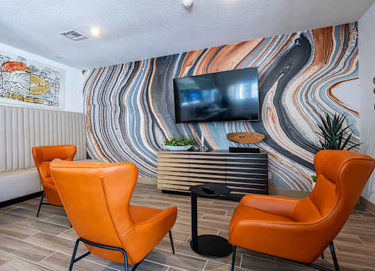 the lobby of a hotel with orange chairs and a television