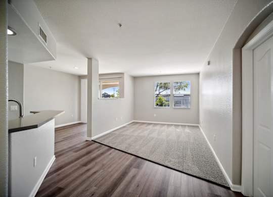 an empty living room and kitchen with white walls and wood floors