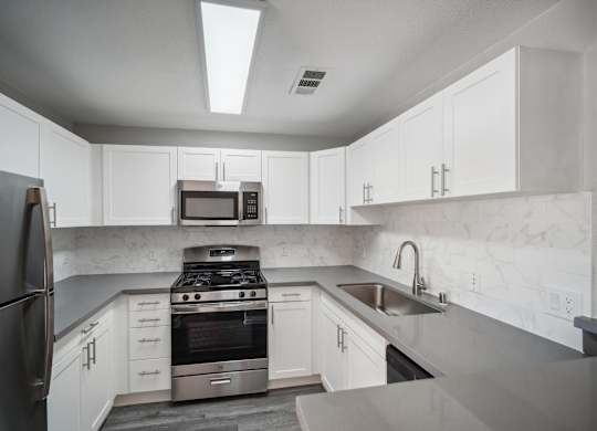 a kitchen with white cabinets and stainless steel appliances