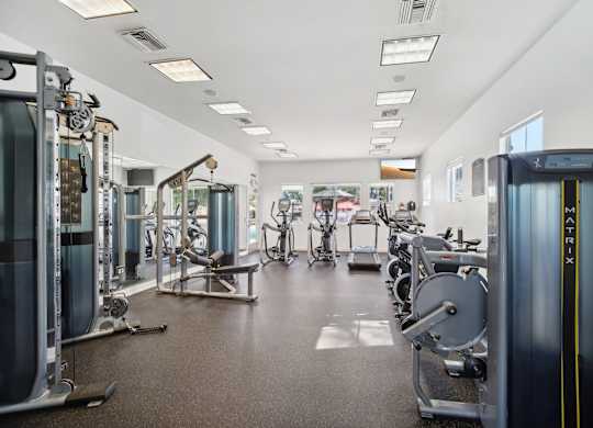 a gym with cardio equipment and weights on the floor