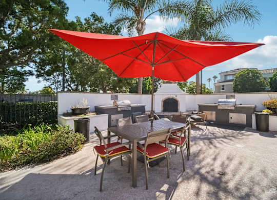 a patio with a table and a red umbrella