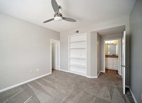 an empty living room with a ceiling fan and a closet