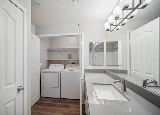 a white laundry room with a sink and a washer and dryer in it