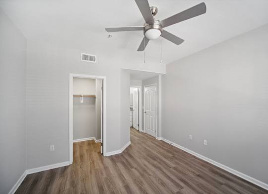 the living room of an empty apartment with a ceiling fan